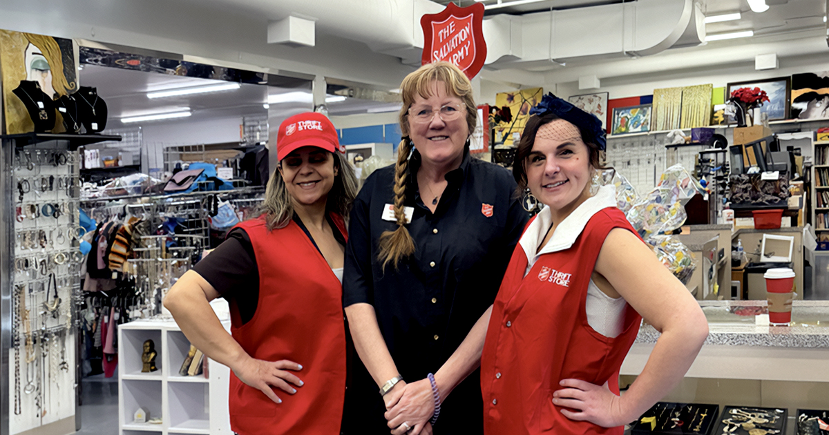 Three women stand together in a thrift store