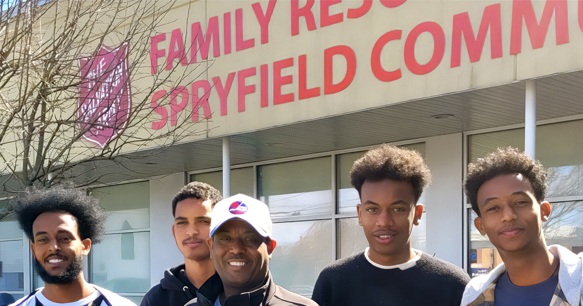 A man and four sons stand together smiling