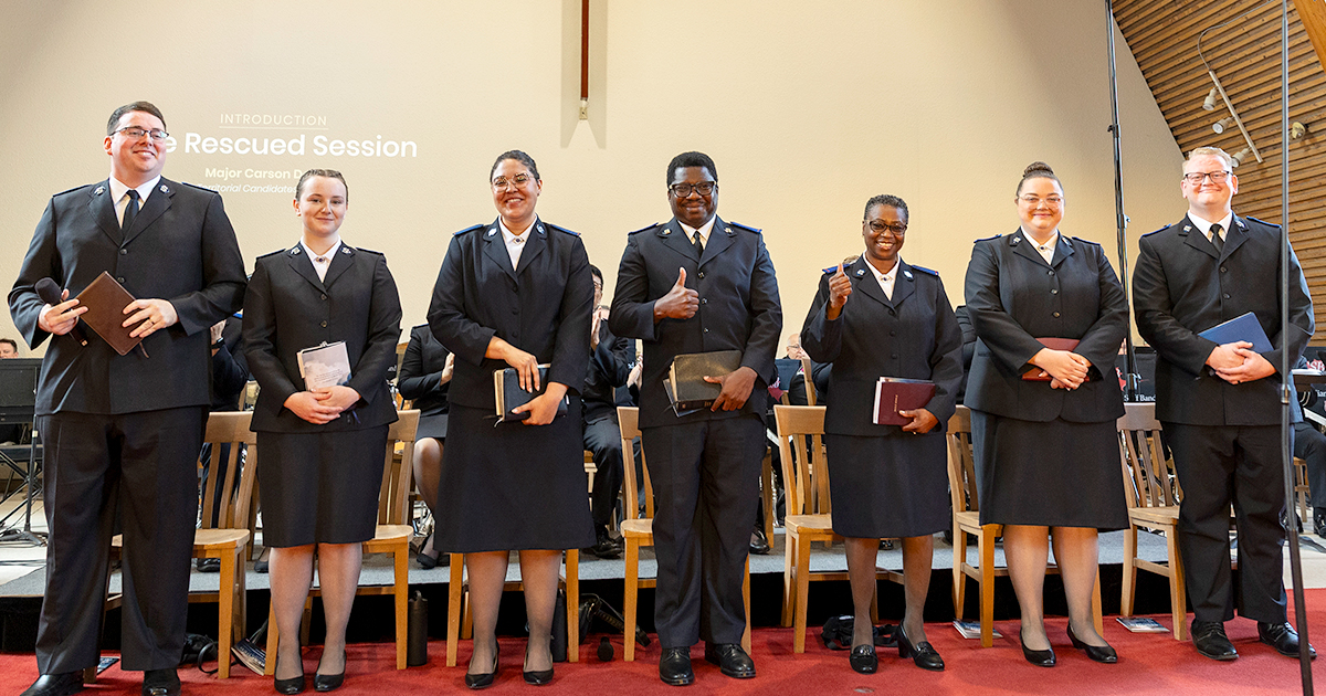 Seven smiling cadets stand at the front of a church